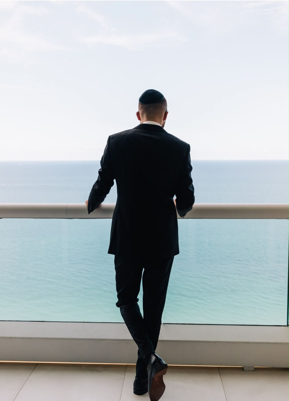 Man in a bespoke Oliel suit overlooking the ocean